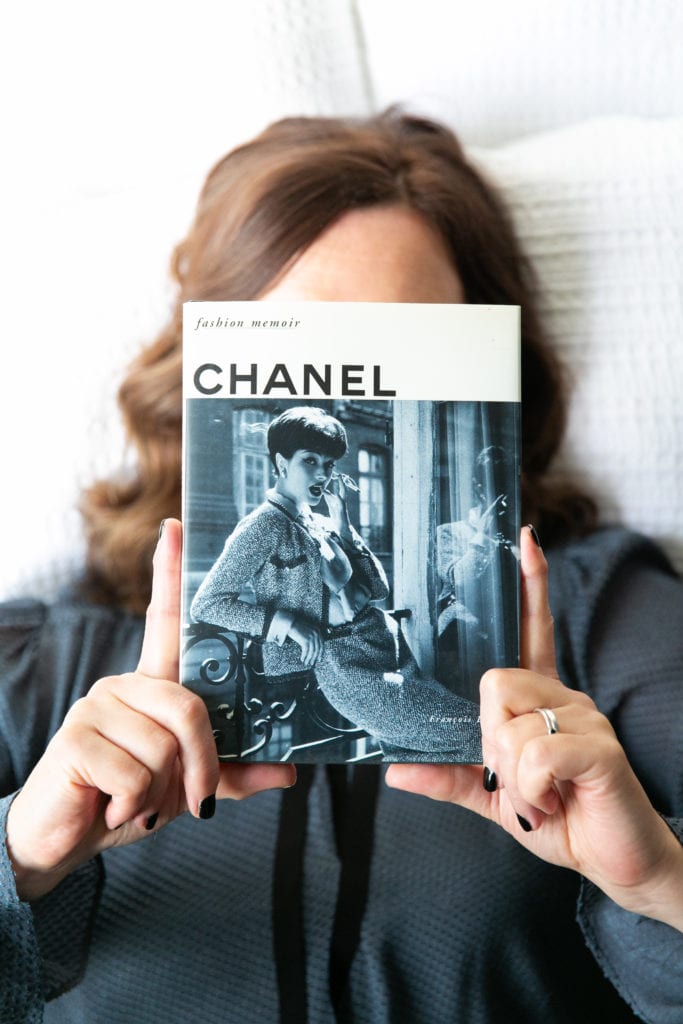 Emma Shard with a chanel book in front of her face.